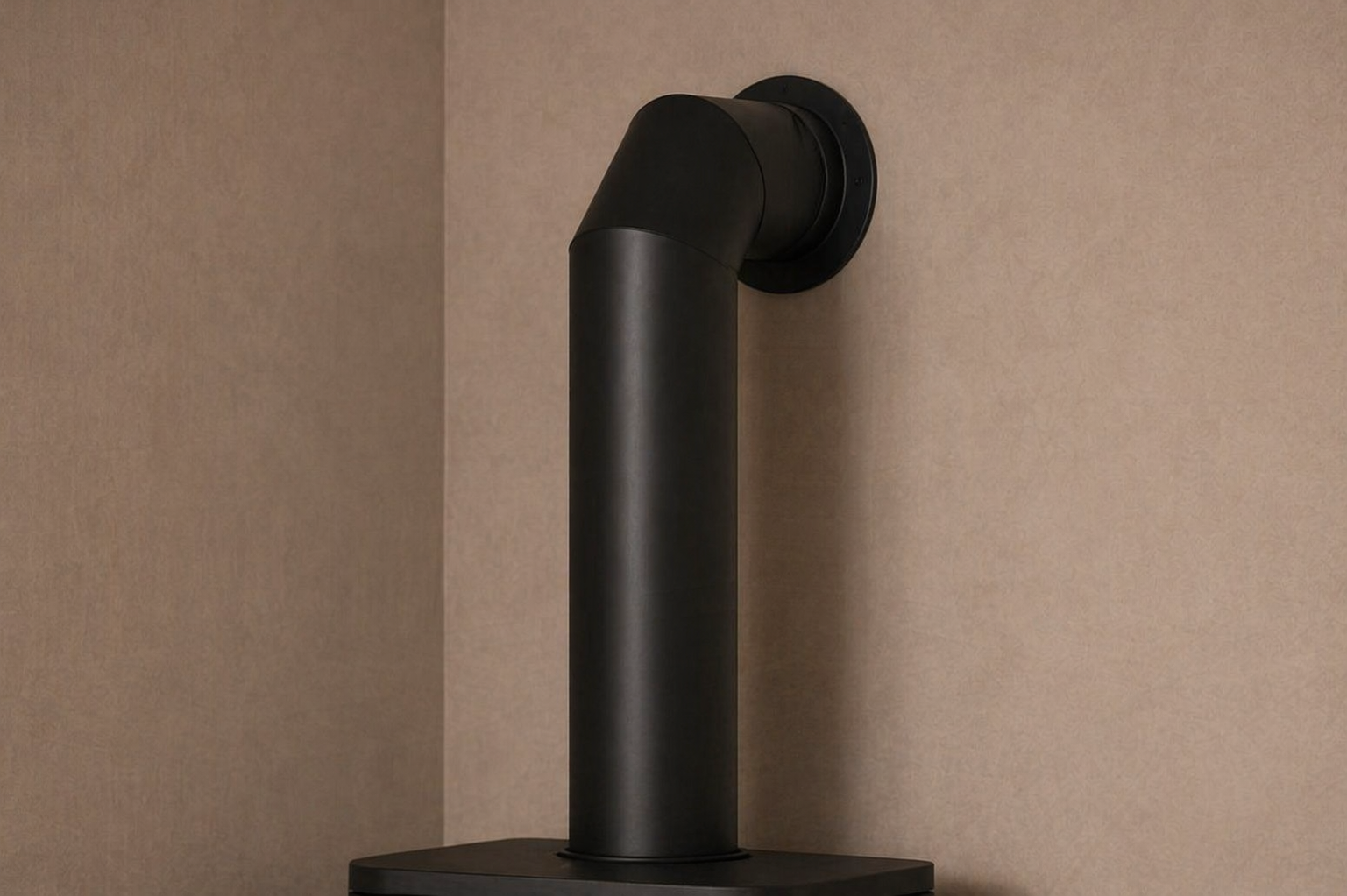 Decoratieve afvoerpijp in mat zwart aan de muur boven een elektrische kachel